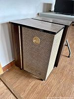 Full view of single speaker cabinet with fabric grille and wood side panel