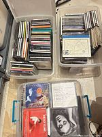 Three plastic bins filled with stacked CDs in jewel cases and sleeves