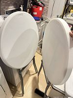 Front view of two folded tables showing white plastic tops and gray legs