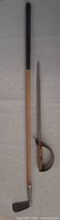 Full view of golf club and saber showing comparative lengths and overall condition