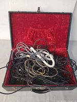 Open case showing red velvet interior and tangled cables