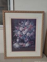 Full view of framed floral still life print with carved gilt frame and mat
