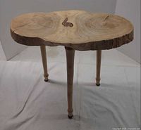 angled view of table showing live edge slab top and three legs