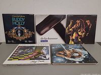 Five album covers: Buddy Holly, Peter Gabriel Sledgehammer, Cheap Trick At Budokan, The J. Geils Band Freeze-Frame, Boney M. Nightflight to Venus