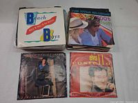 Stack of singles topped by Beach Boys, John Cougar Mellencamp, Bruce Springsteen, Elvis Costello picture sleeves