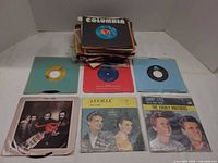 Stack of approximately 60 7-inch singles with several picture sleeves visible