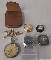 Group shot showing all watches, chain, inserts, leather pouch