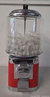 Full view of red and chrome tabletop vending machine with capsules inside