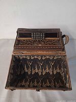 Accordion positioned inside open lined trunk showing decorative lid and interior
