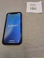 iPhone XR front powered on showing Korean greeting on hello setup screen