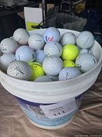 Bucket filled with assorted used golf balls