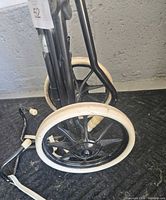 Close view of wheels and lower frame of the golf cart showing black spokes and white tires