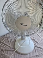Front view of Hawaiian Breeze white tabletop fan showing grille, blades and base