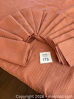 Peach patterned linen tablecloth laid out with twelve matching napkins fanned on top