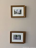 Both framed prints displayed vertically on wall