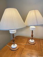 Both matching hobnail milk glass table lamps with shades on wood table
