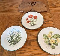 Overview of three floral plates and carved wood panel on wooden surface