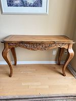 Full frontal view of solid wood console table showing carved apron and cabriole legs