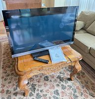 Front view of Sony Bravia TV on table with remote and manual