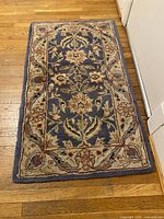 Full view of the rectangular blue and cream floral rug on hardwood floor