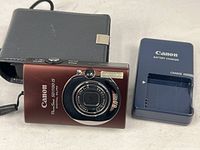 Front view of Canon PowerShot SD1100 IS with charger and pouch