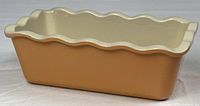Side view of ceramic loaf pan showing peach exterior and wavy rim