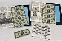Overview showing folders with uncut note sheets, loose $2 note, and quarter saver card