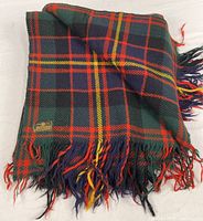 Full view folded tartan blanket showing pattern and fringe