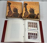 Three stamp albums including two Statue of Liberty volumes and maroon binder