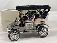 Profile of metal miniature antique car with clock dial visible