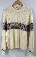 Full front view of cream cable-knit sweater showing geometric chest band