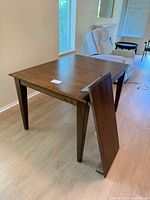 Dining table with leaf standing beside showing attachment hardware