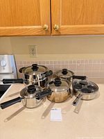 Five Lagostina stainless pans with lids grouped on countertop