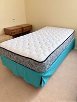Full view of assembled twin mattress on box spring with teal bed skirt