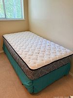 Full view of mattress on box spring with teal bedskirt