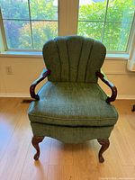front view of green upholstered armchair showing fabric, wood arms, cabriole legs