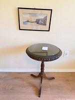 Side table with glass top and framed art on wall