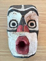 Front view of painted wood mask showing facial features and paint