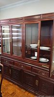 Full view of china cabinet showing glass upper section, drawers, and carved lower doors