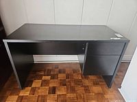 Front view of black desk showing drawers and overall form