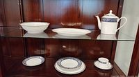 Coffee pot, oval platter, serving bowl and assorted place setting pieces on cabinet shelf