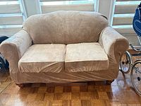 Front view of tan slipcovered loveseat showing two cushions and overall style