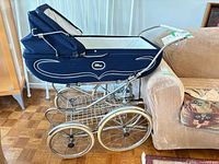 Side view of navy baby carriage showing chrome frame, wheels, basket, hood and body