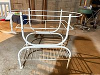 Side view of white metal stand showing frame, wheels, lower shelf