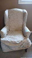Front view of upholstered wingback chair with slipcover