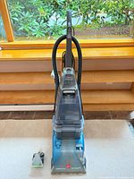 Full view of Hoover SpinScrub 50 with hose and accessory on floor