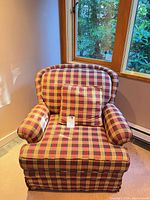 Front view of plaid skirted armchair with throw pillow