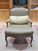 Front view of French style armchair with gingham upholstery and lumbar pillow