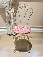 Front view of brass vanity chair showing scroll back and upholstered seat