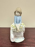 Front view of figurine showing girl holding flower basket